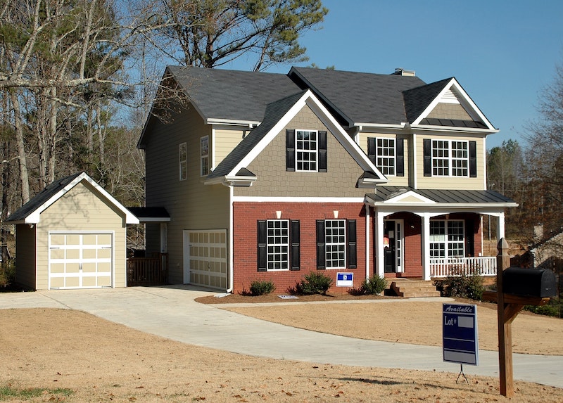 two story home with for sale sign in front